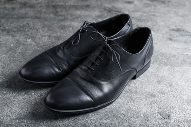 Photo of Pair of black leather shoes on grey surface, closeup