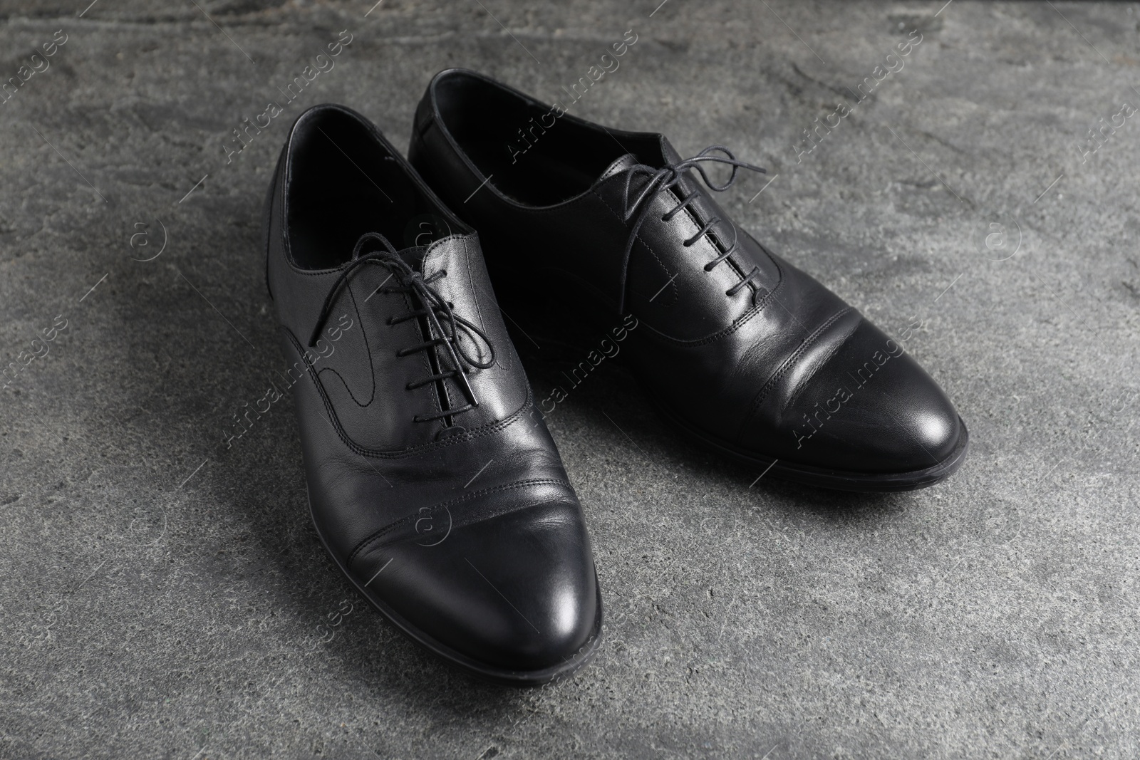 Photo of Pair of black leather shoes on grey surface