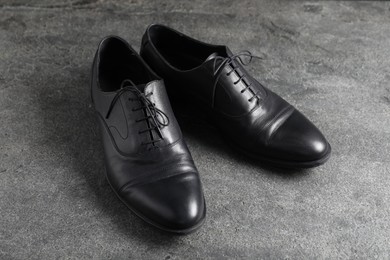 Photo of Pair of black leather shoes on grey surface