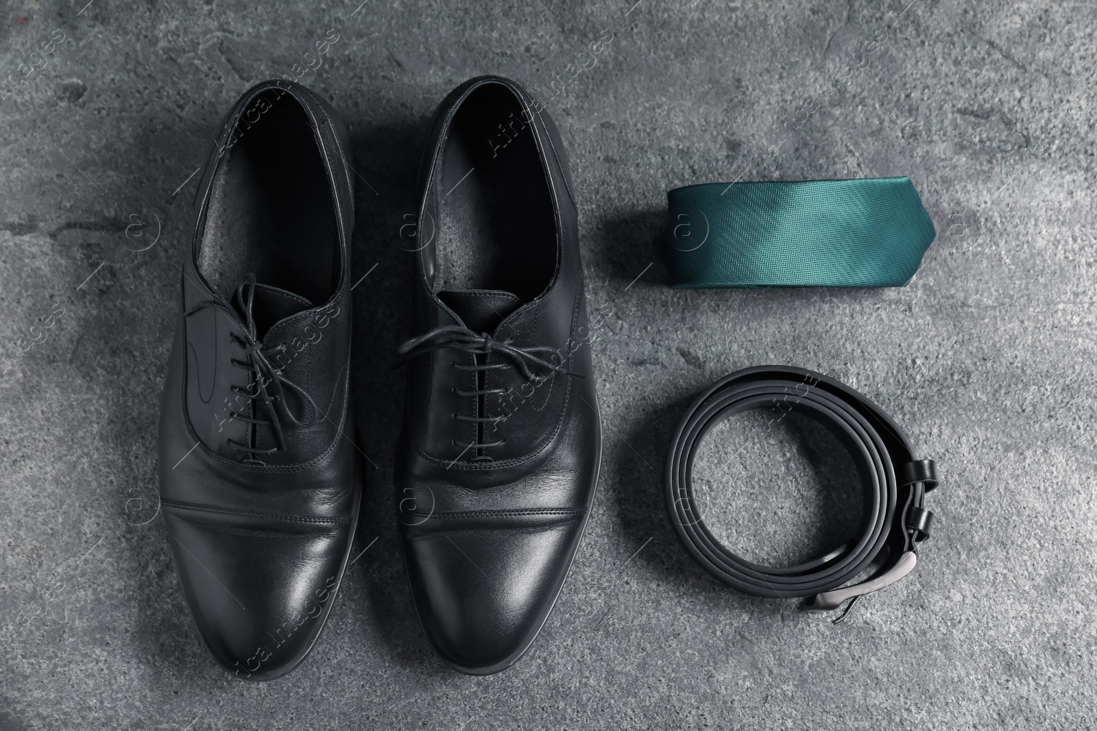 Pair of black leather shoes, belt and necktie on grey surface, flat lay Photo of Pair of black leather shoes, belt and necktie on grey surface, flat lay
