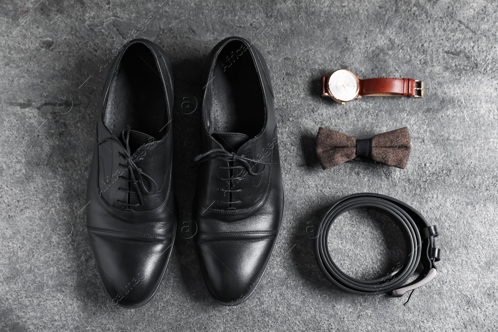 Pair of black leather shoes, wrist watch, belt and bow tie on grey surface, flat lay Photo of Pair of black leather shoes, wrist watch, belt and bow tie on grey surface, flat lay