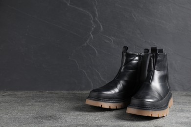 Photo of Pair of stylish black boots on grey surface, space for text