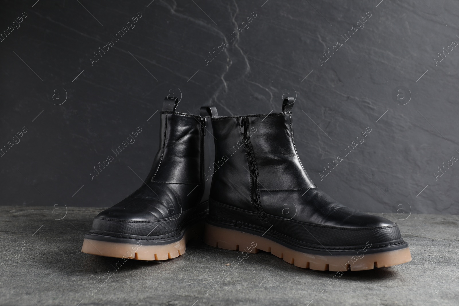 Pair of stylish black boots on grey surface Photo of Pair of stylish black boots on grey surface