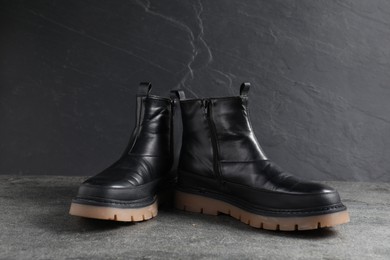 Photo of Pair of stylish black boots on grey surface