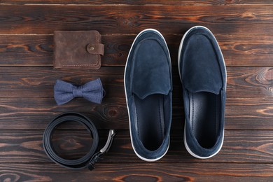 Photo of Pair of dark blue shoes, belt, bow tie and purse on wooden surface, flat lay