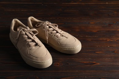 Photo of Pair of beige sneakers on wooden surface, space for text