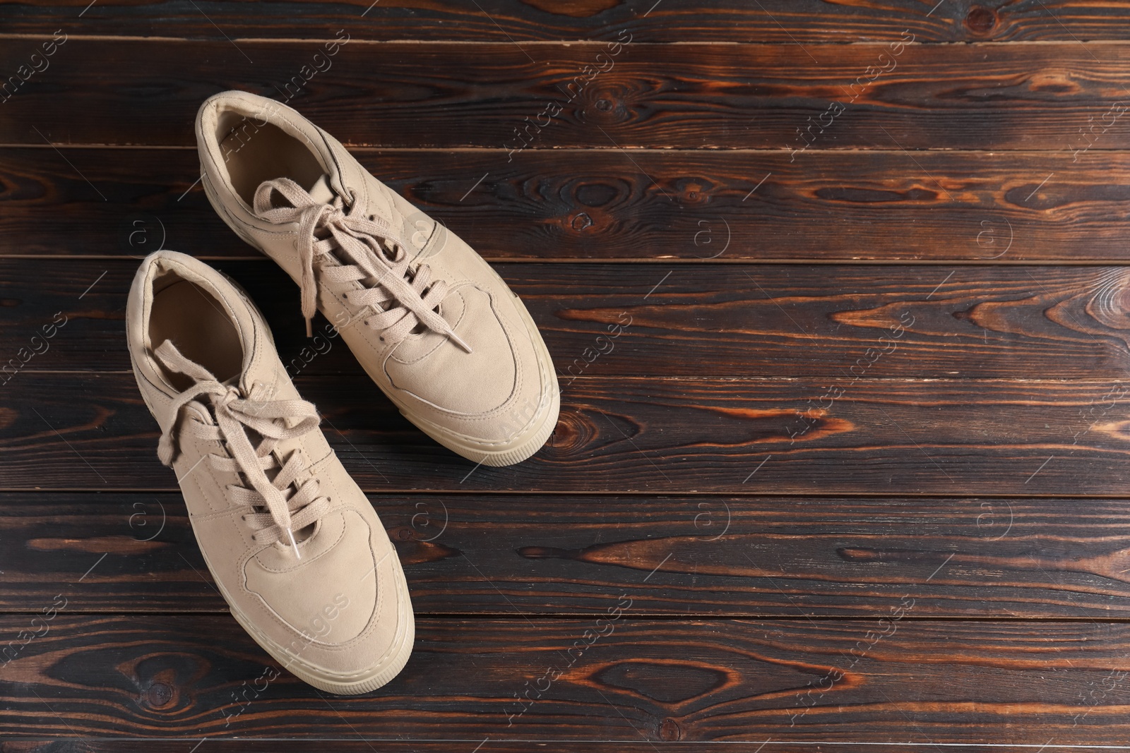 Photo of Pair of beige sneakers on wooden surface, flat lay. Space for text