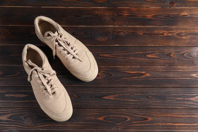 Photo of Pair of beige sneakers on wooden surface, flat lay. Space for text