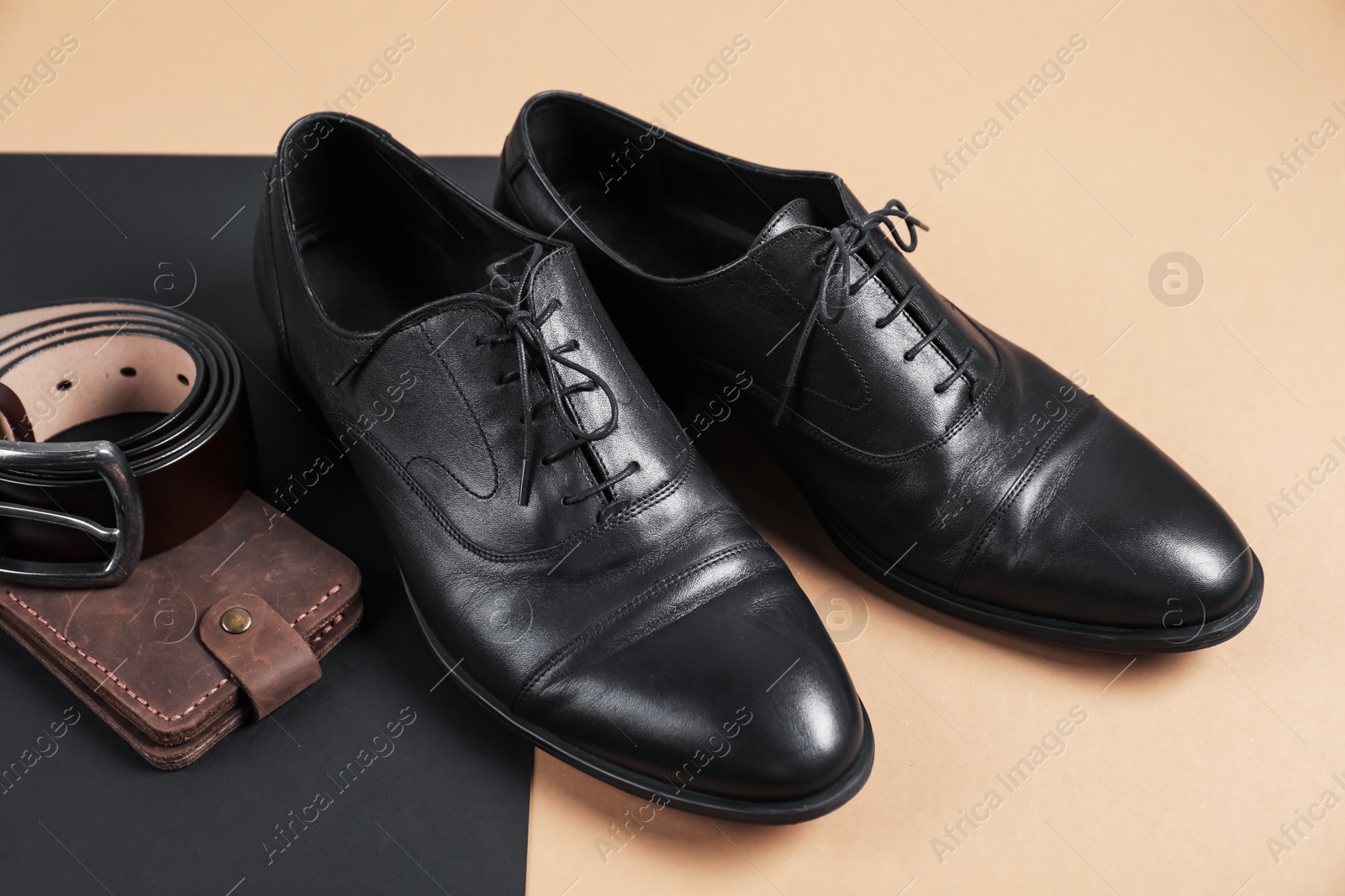Photo of Pair of black leather shoes, purse and belt on color background, closeup
