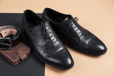 Photo of Pair of black leather shoes, purse and belt on color background, closeup