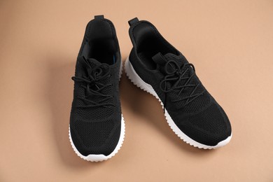 Photo of Pair of black sneakers on beige background