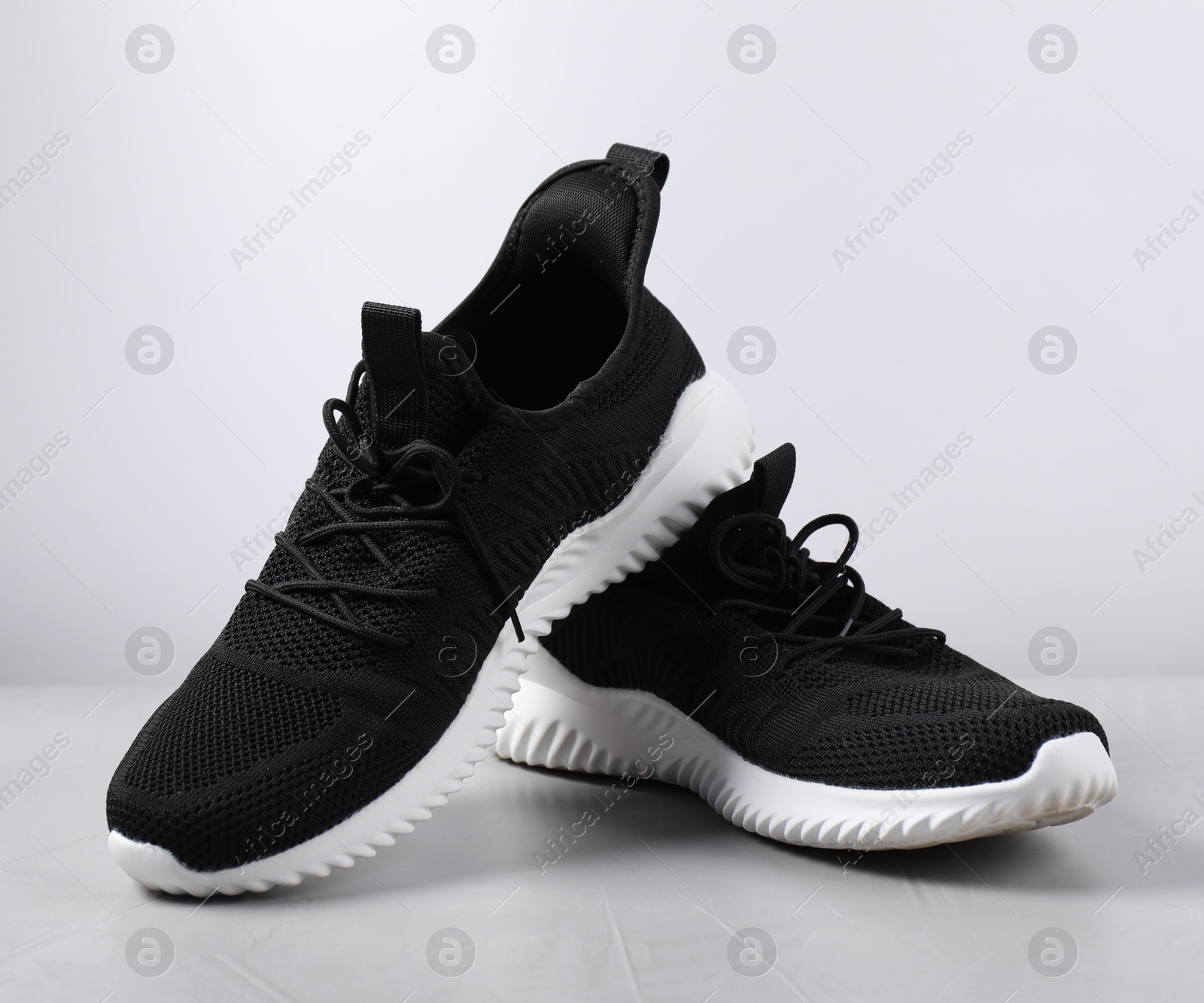Photo of Pair of black sneakers on light grey surface