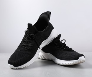 Photo of Pair of black sneakers on light grey surface