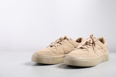 Photo of Pair of beige sneakers on light grey surface, closeup. Space for text