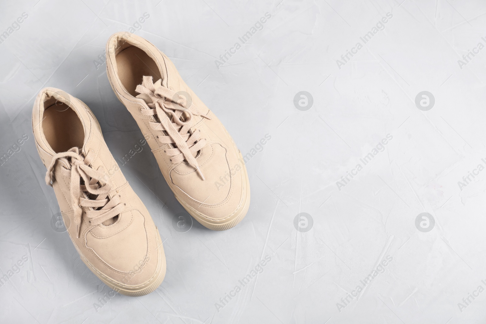 Photo of Pair of beige sneakers on light grey surface, flat lay. Space for text
