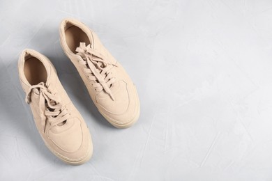 Photo of Pair of beige sneakers on light grey surface, flat lay. Space for text