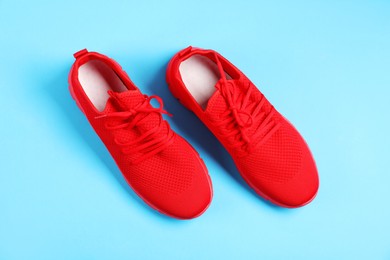 Photo of Pair of red sneakers on light blue background, flat lay