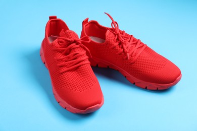 Photo of Pair of red sneakers on light blue background, closeup