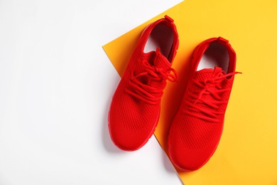 Photo of Pair of red sneakers on color background, flat lay. Space for text