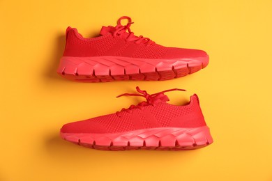 Photo of Pair of red sneakers on orange background, flat lay