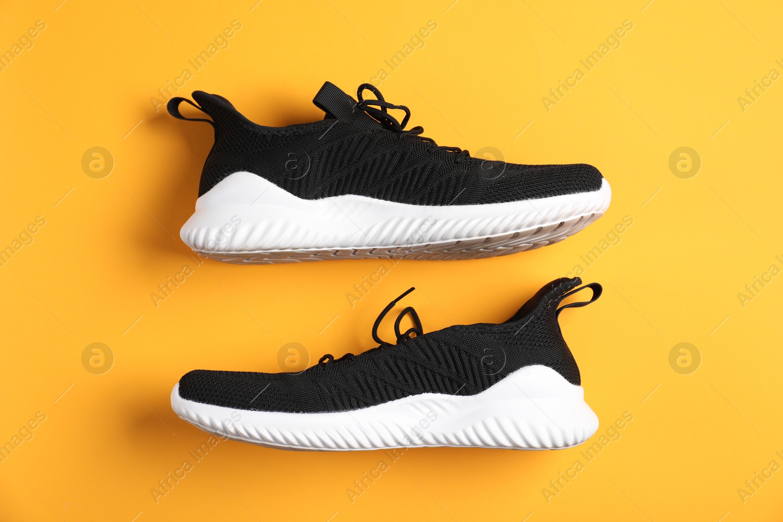 Photo of Pair of black sneakers on orange background, flat lay