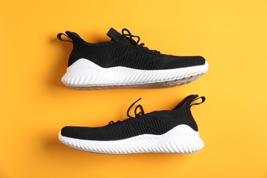 Photo of Pair of black sneakers on orange background, flat lay