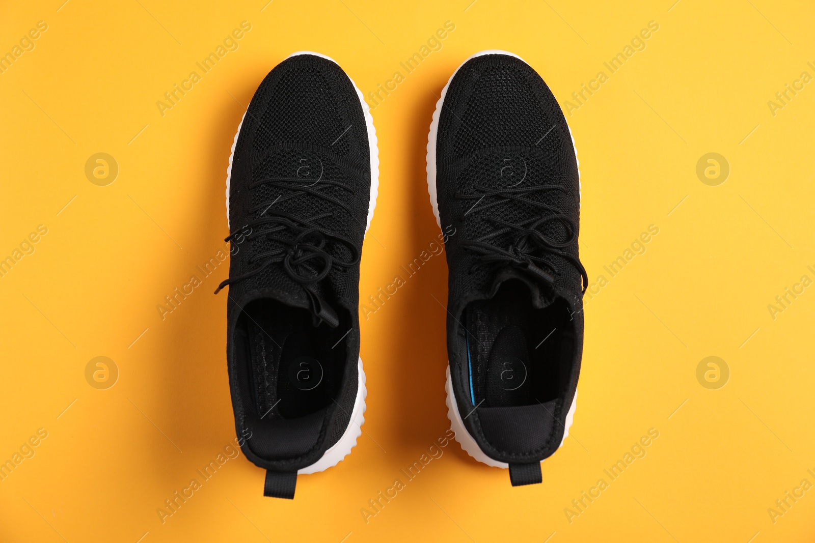 Photo of Pair of black sneakers on orange background, flat lay