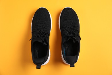 Photo of Pair of black sneakers on orange background, flat lay
