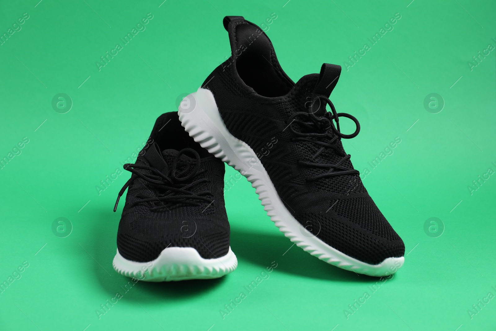 Photo of Pair of black sneakers on green background