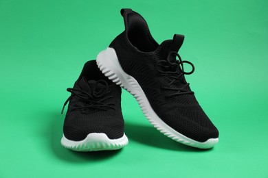 Photo of Pair of black sneakers on green background