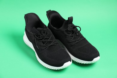 Photo of Pair of black sneakers on green background