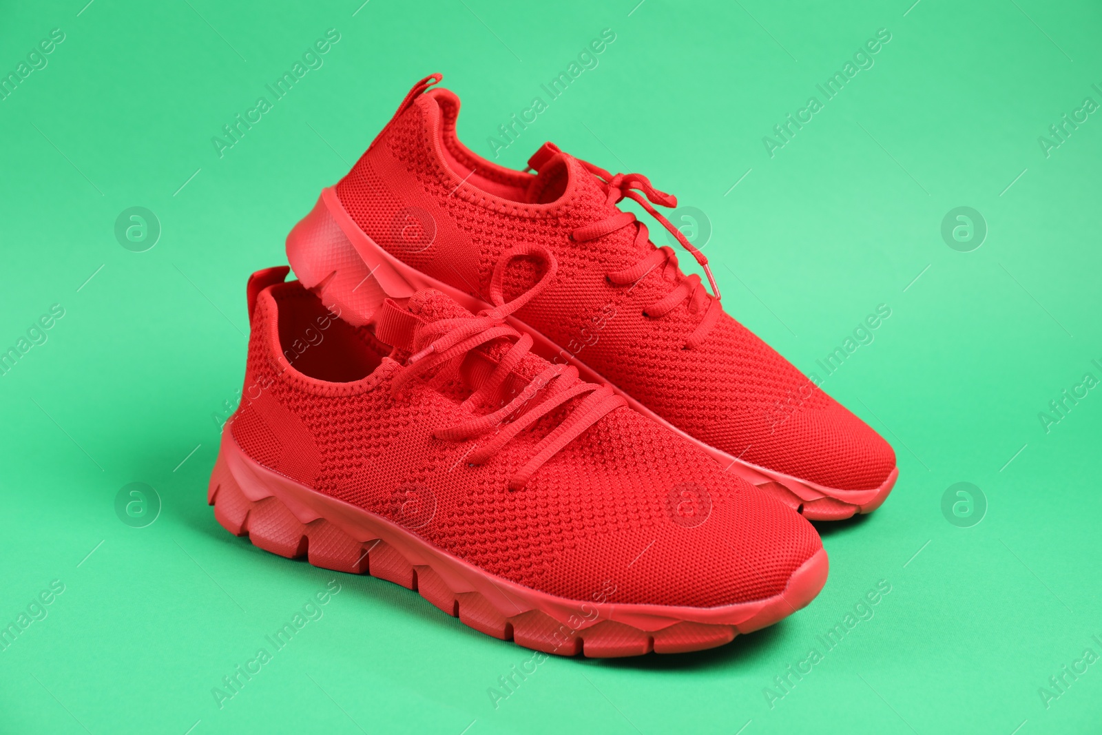 Photo of Pair of red sneakers on green background