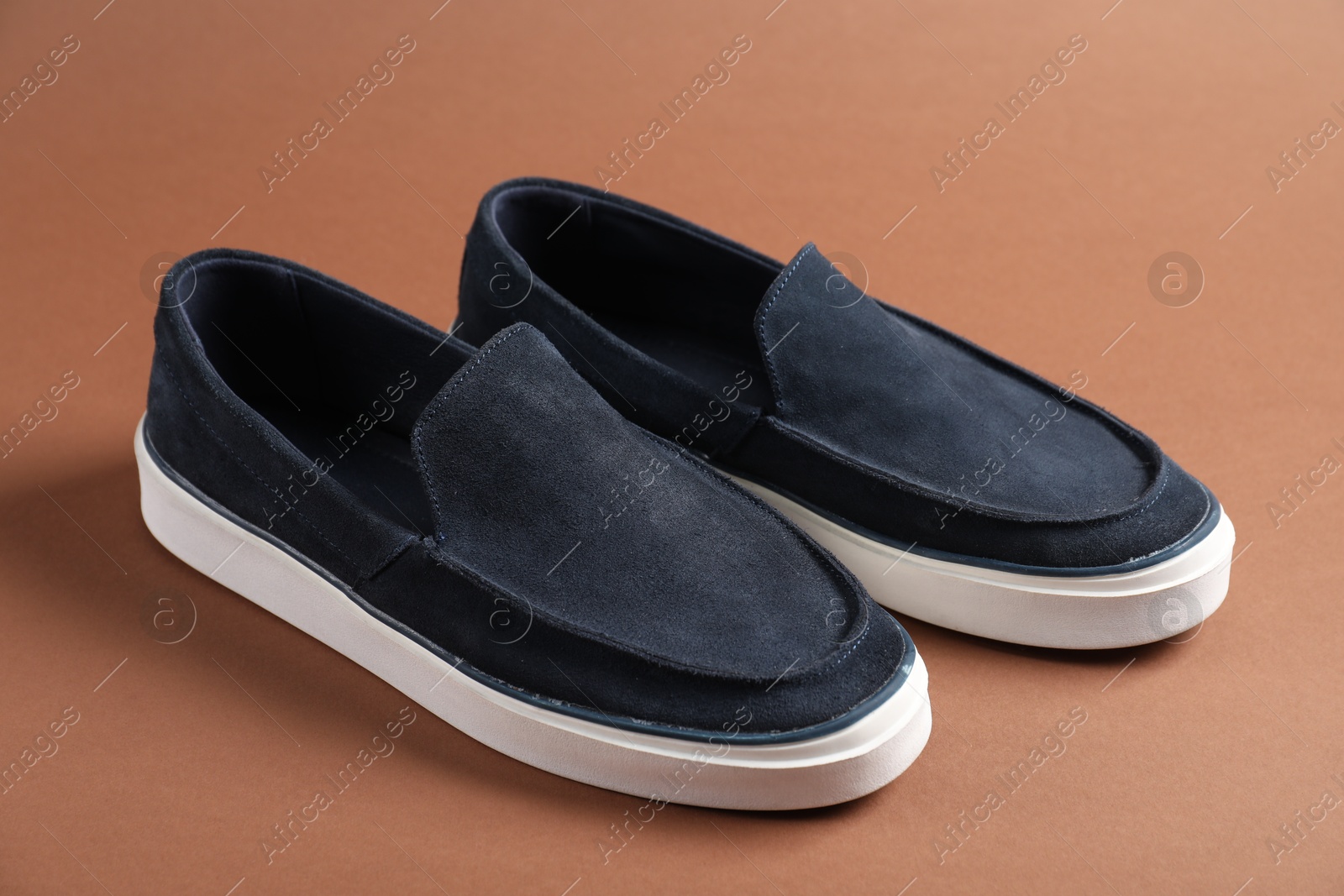 Photo of Pair of dark blue shoes on dark beige background, closeup