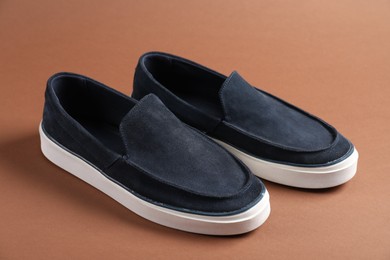 Photo of Pair of dark blue shoes on dark beige background, closeup