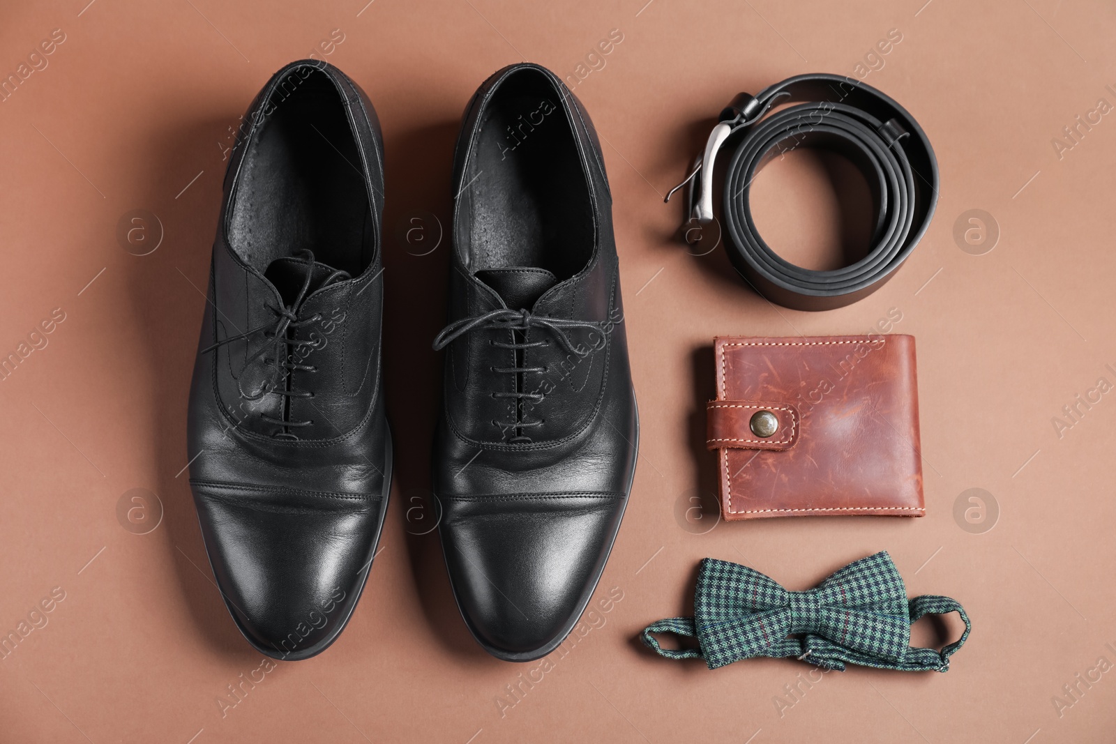 Pair of black leather shoes, belt, bow tie and purse on dark beige background, flat lay Photo of Pair of black leather shoes, belt, bow tie and purse on dark beige background, flat lay
