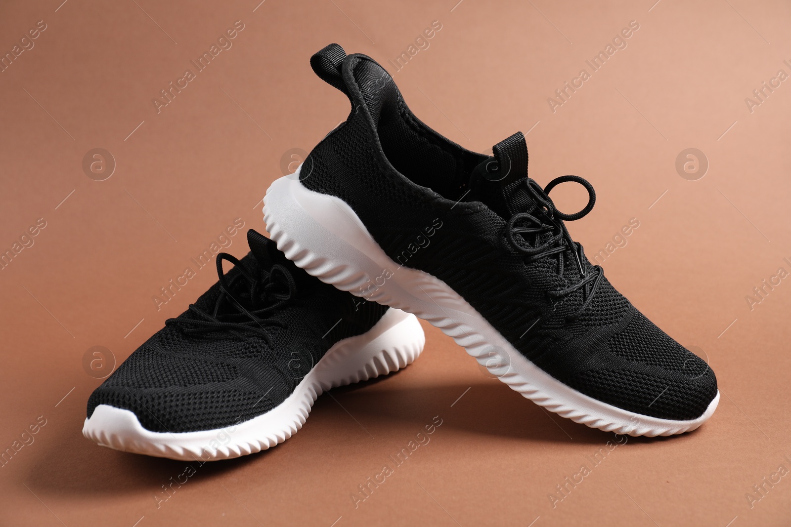 Photo of Pair of black sneakers on dark beige background