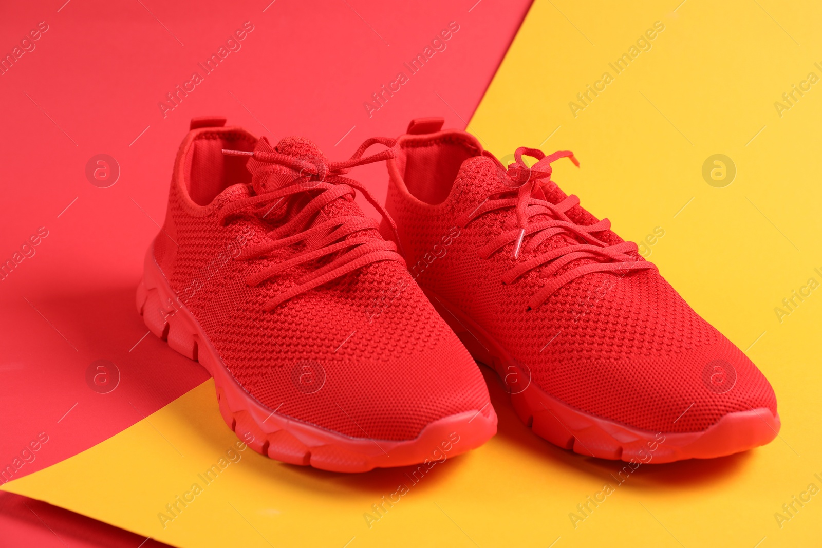 Photo of Pair of red sneakers on color background, closeup