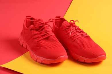 Photo of Pair of red sneakers on color background, closeup