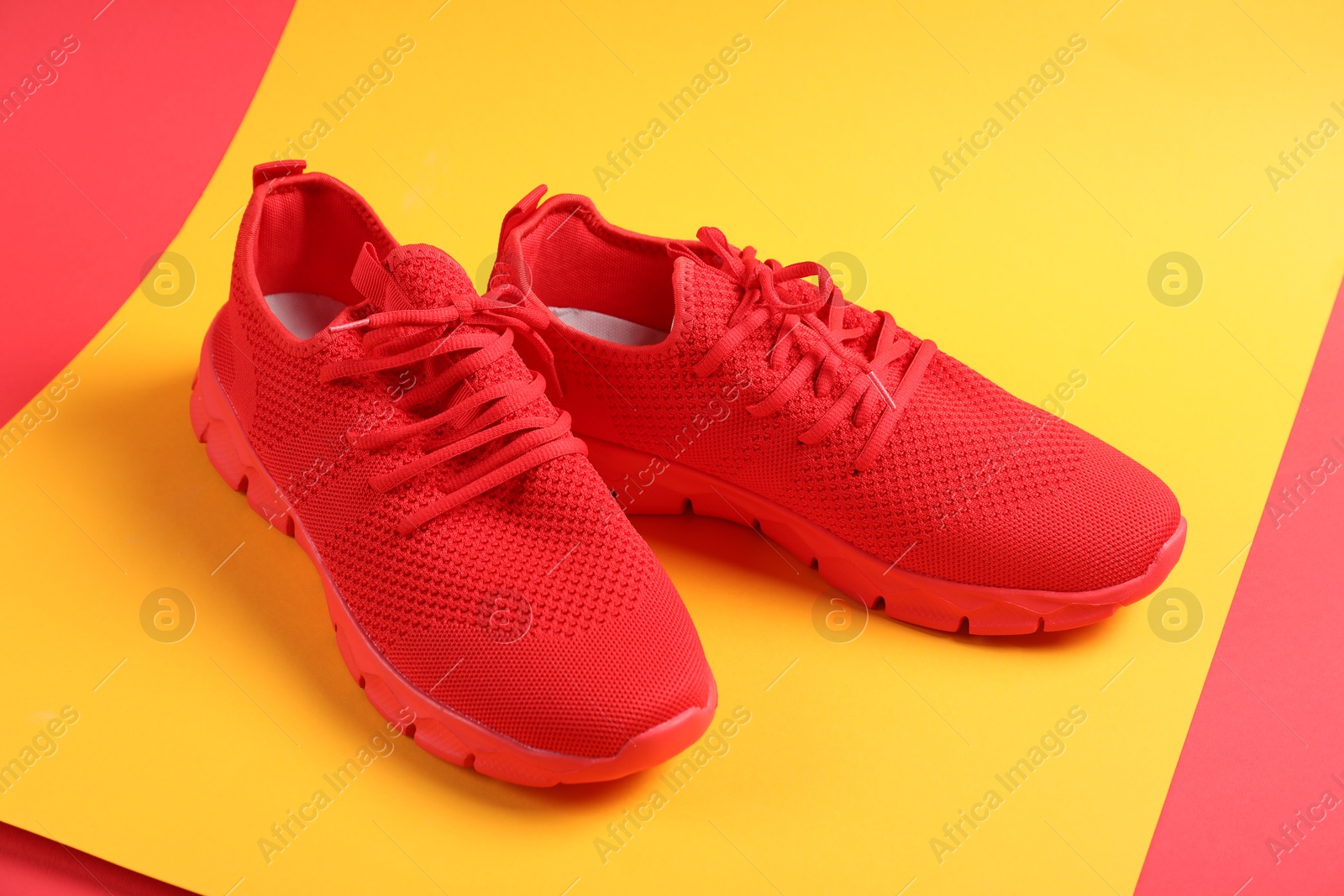 Photo of Pair of red sneakers on color background