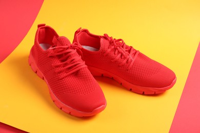 Photo of Pair of red sneakers on color background