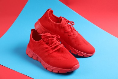 Photo of Pair of red sneakers on color background