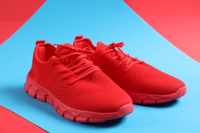 Photo of Pair of red sneakers on color background, closeup