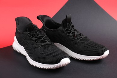 Photo of Pair of black sneakers on color background, closeup