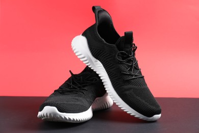 Photo of Pair of black sneakers on color background