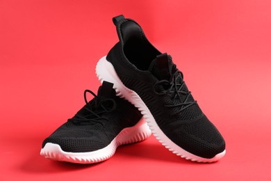 Photo of Pair of black sneakers on red background