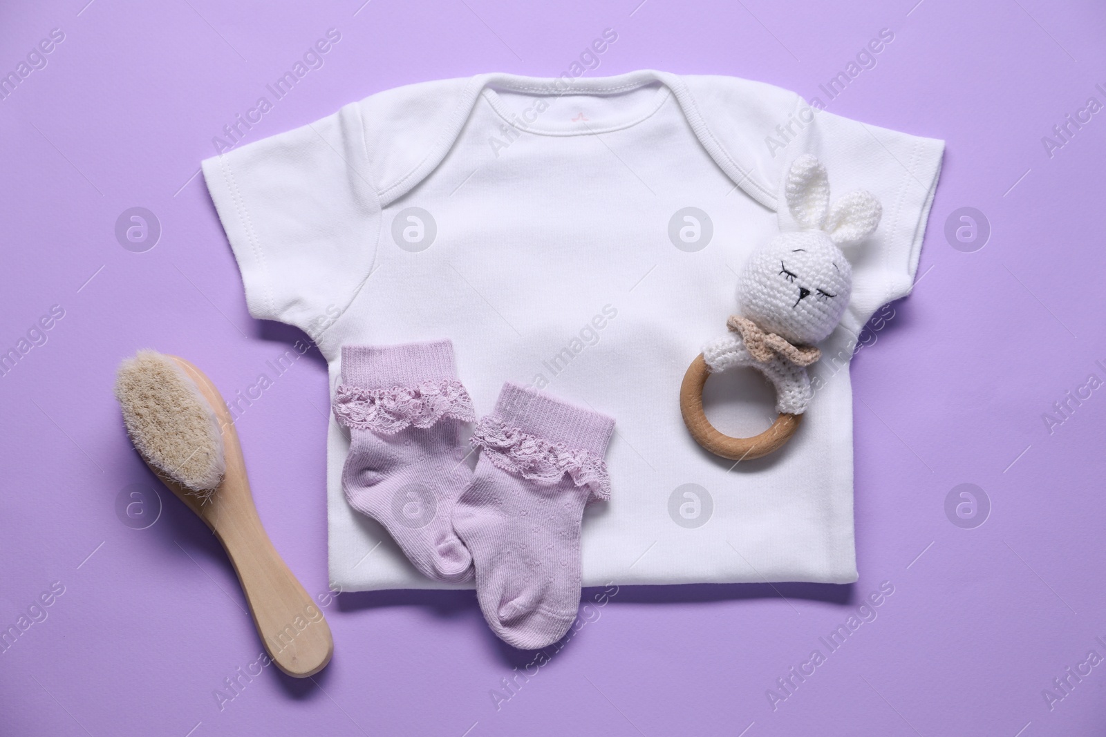 Baby clothes and accessories on violet background, flat lay Photo of Baby clothes and accessories on violet background, flat lay