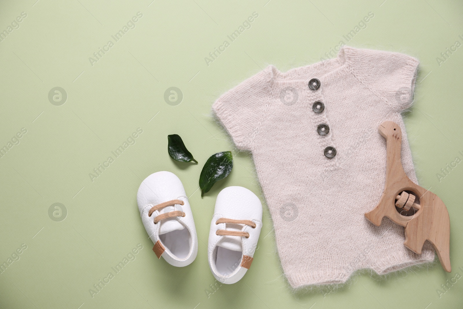 Photo of Baby clothes and accessory on light green background, flat lay. Space for text