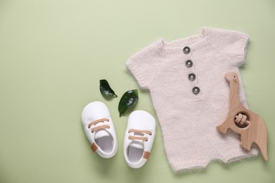Photo of Baby clothes and accessory on light green background, flat lay. Space for text