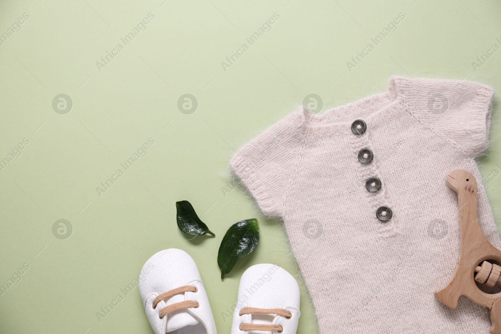 Photo of Baby clothes and accessory on light green background, flat lay. Space for text