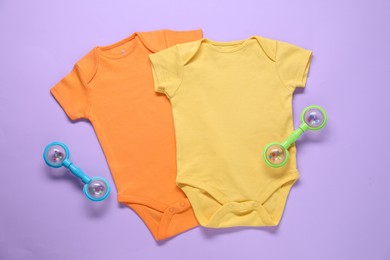 Photo of Bright baby onesies and accessories on violet background, flat lay